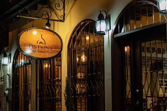 Fachada nocturna de Pistrina con letrero colgante iluminado